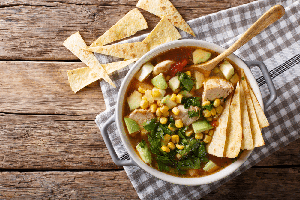 Freshly cooked tortilla soup with chicken and vegetables close up on the table