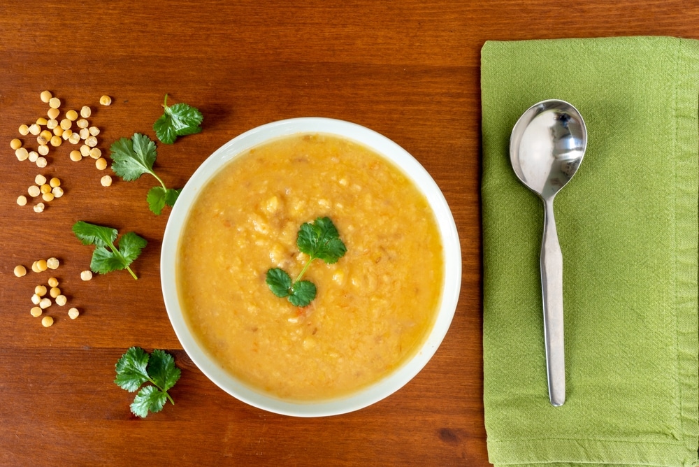 Yellow Split Peas Lentil Soup Garnished With Corrinader Leaves  and a spoon