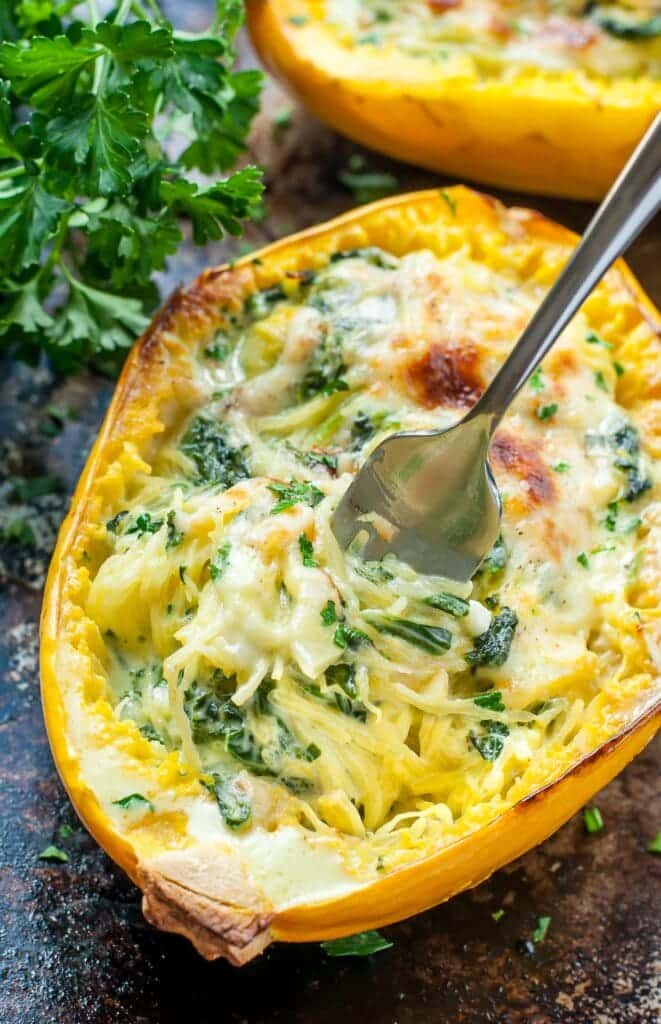 A cheesy spinach spaghetti squash boat with a fork