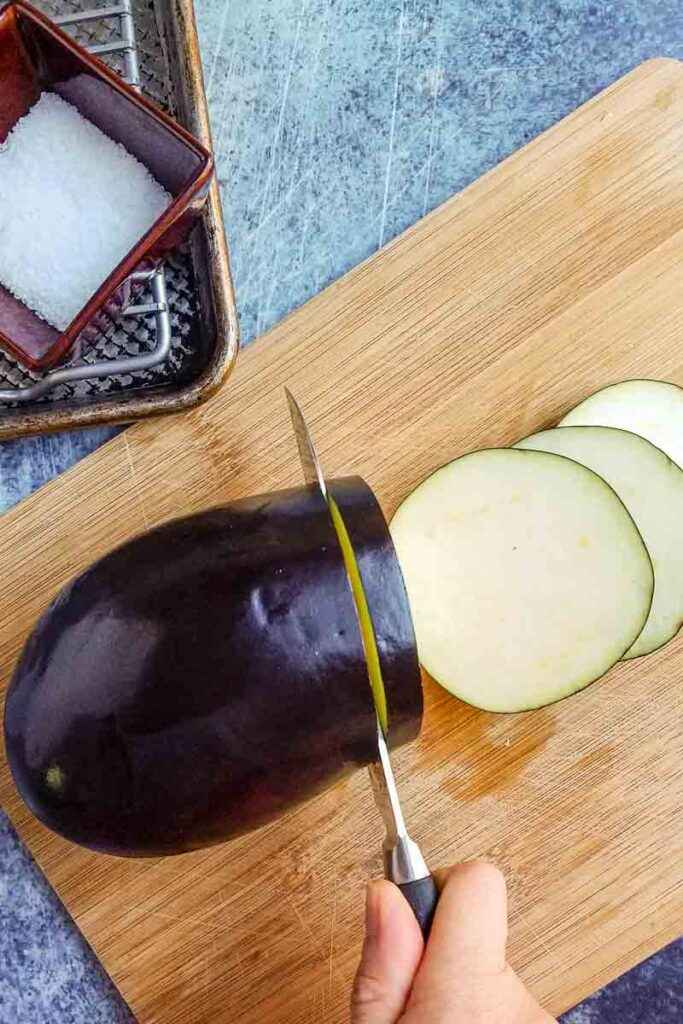 A top view of an eggplant being sliced on a board