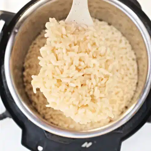 A top view of arborio rice in a pot with some in a ladle