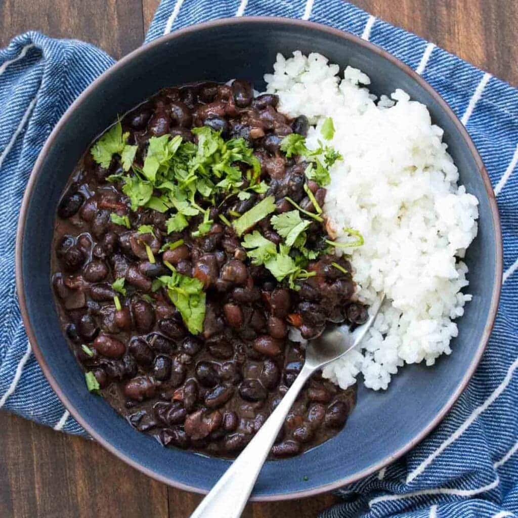 A top view of black beans served with rice in a bowl with cilantro topping