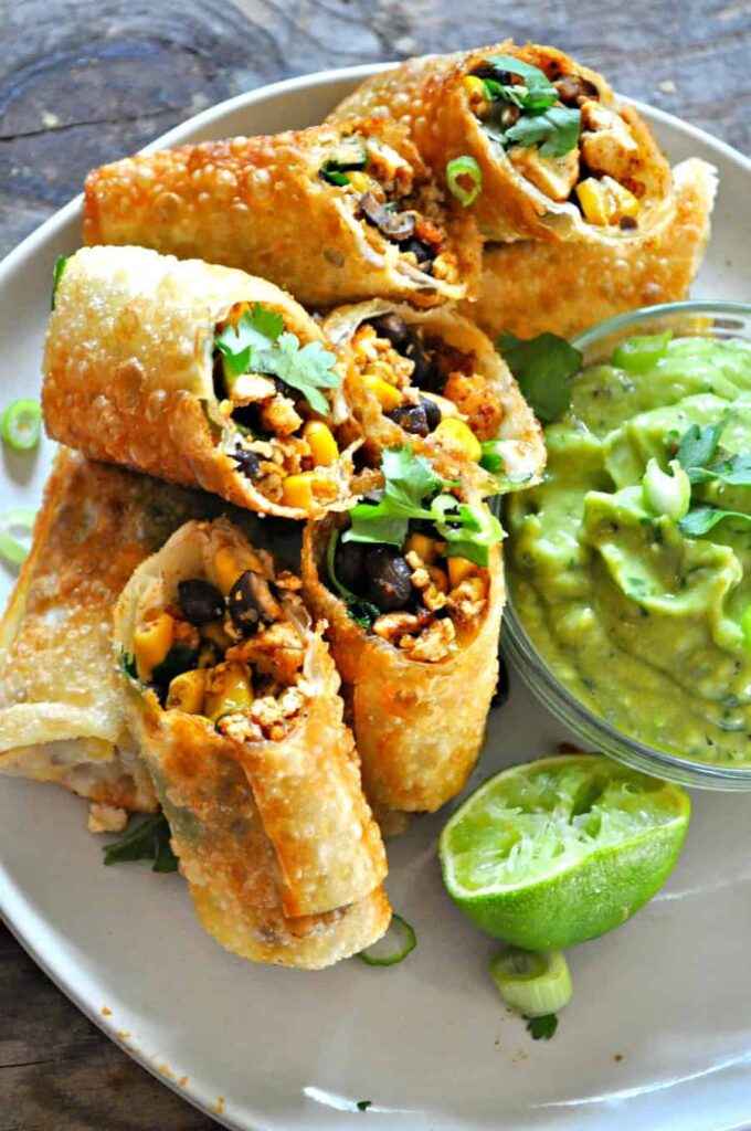 A top view of half sliced vegetable corn egg rolls with green sauce