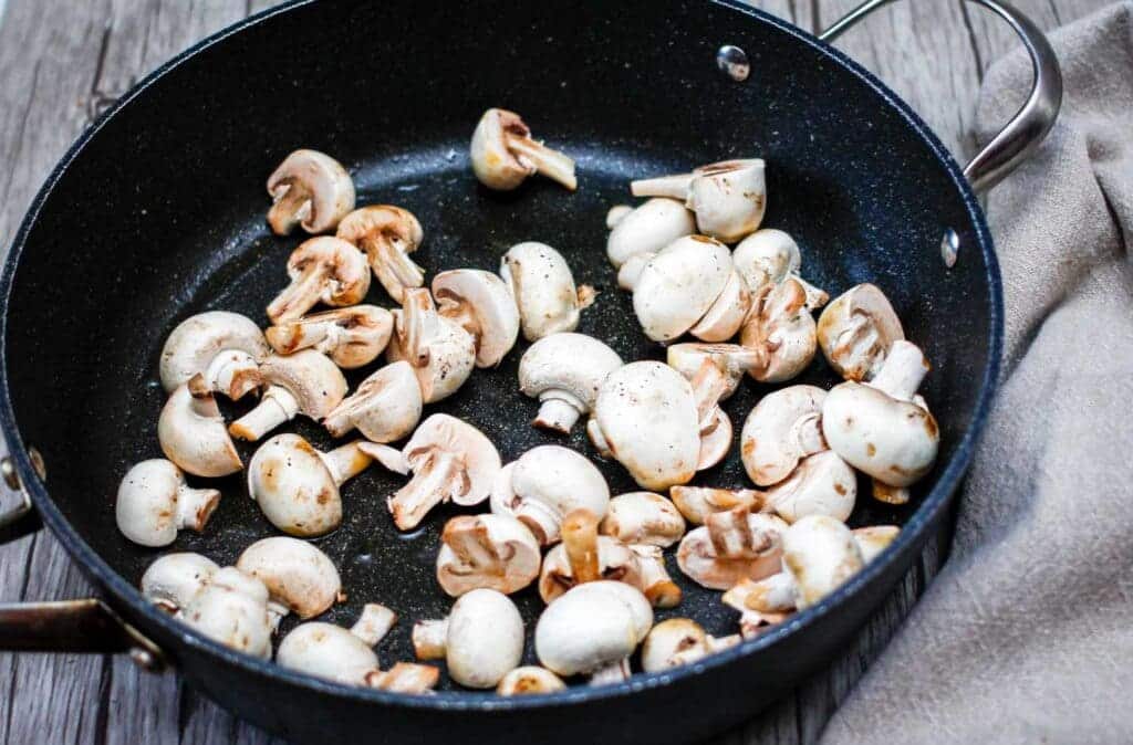 A view of a mushroom being sliced on the cutting board