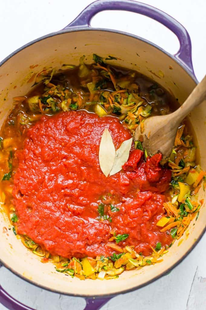 A top view of veggies being sauteed along with pasta sauce inside a pot