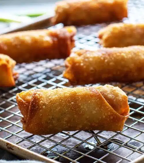 A view of egg rolls sitting on a cooling rack