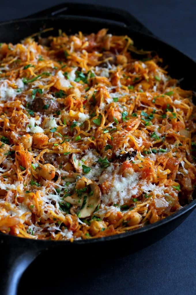 A view of spaghettis squash skillet in a pan with veggies and parmesan cheese topping