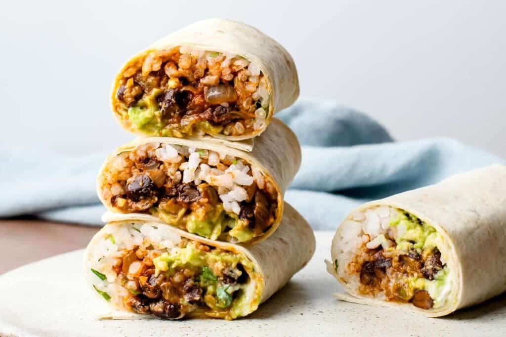 A view of three veg black bean rice burritos on top of one another