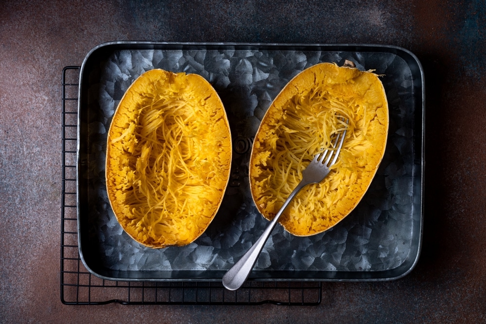 An overhead view of spaghetti squash on baking tray