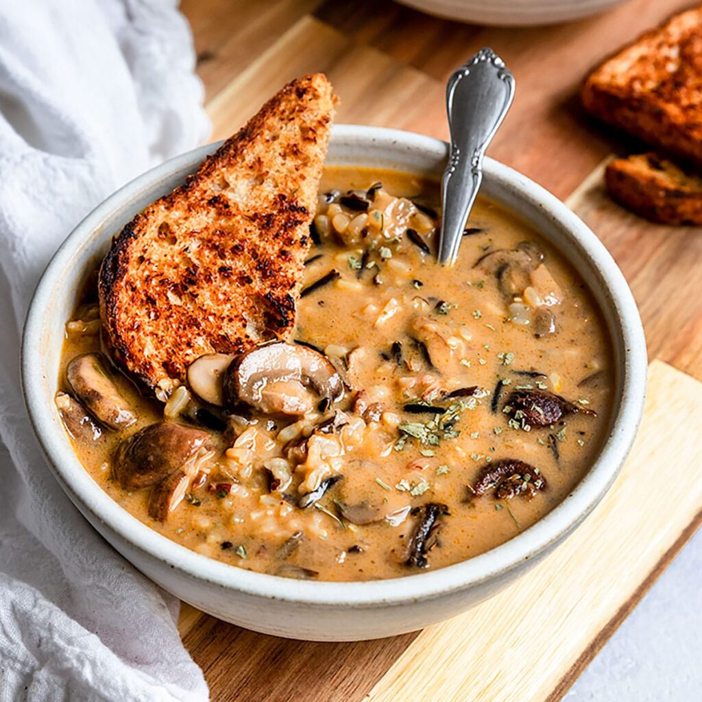 a bowl of wild rice and mashroom soup serve with garlic bread