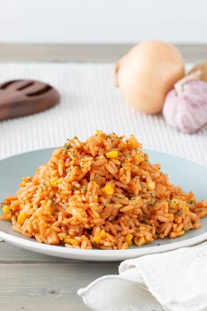 toamto and corn mexican rice in a plate along with onion and garlic