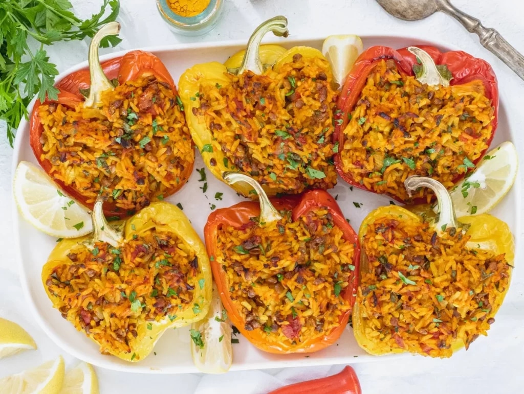 wild rice stuffed bell peppers garnish with lemon wedges in a baking dish