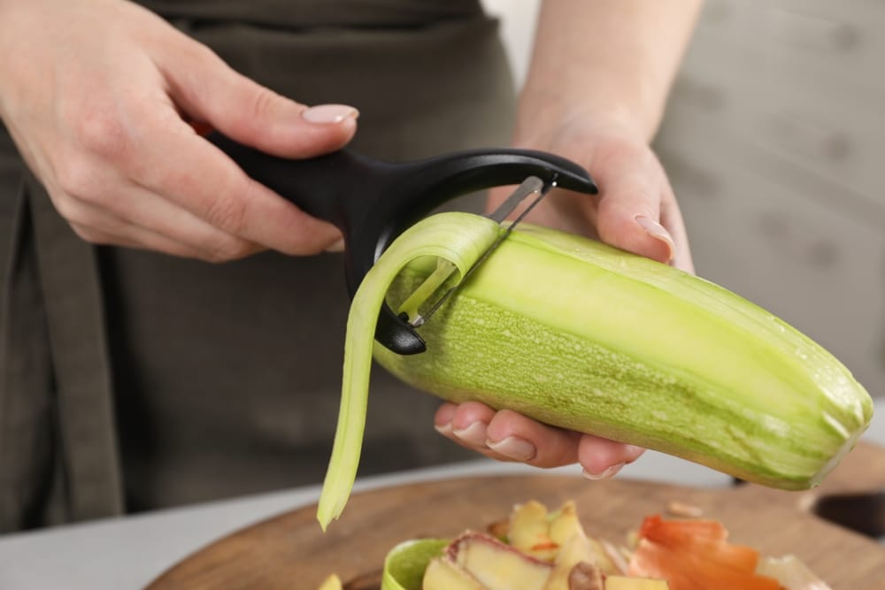 A view of a woman peeling off zucchinis