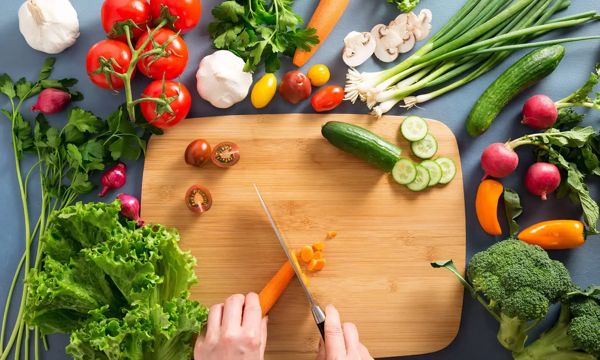 A top view of a person chopping veggies on a wooden board