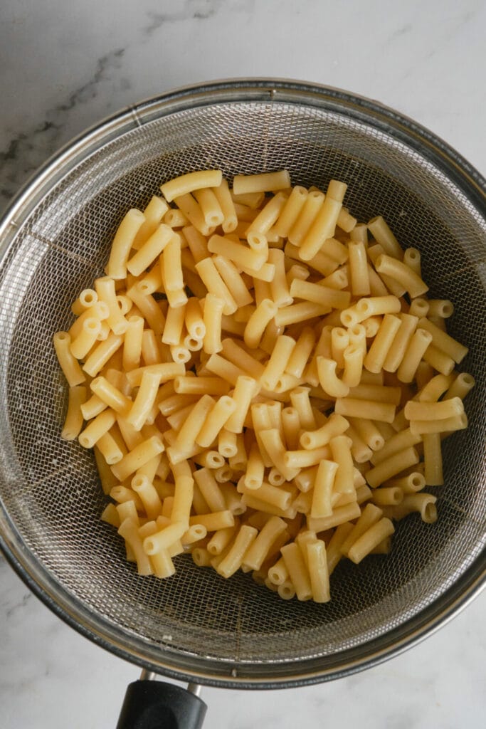 A top view of ziti being strained after being boiled