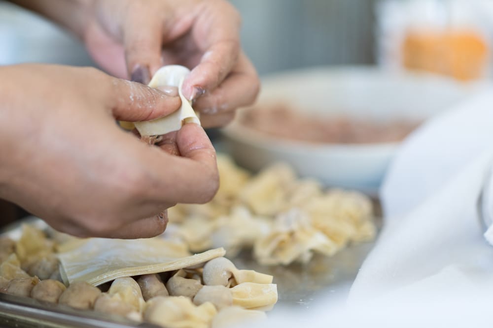 A view of a hand wrapping dumplings