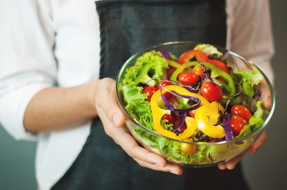 A view of a person holding a bowl of salad