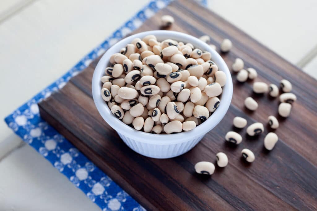 Close up of black eyed peas in bowl on cutting board