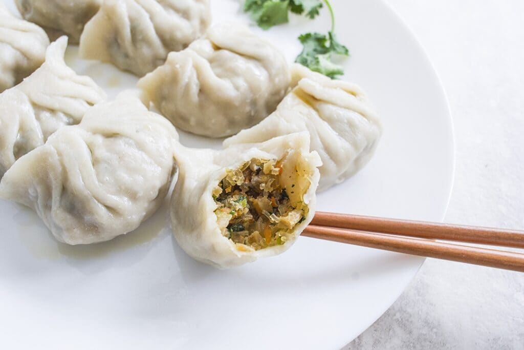 A view of dumplings with one half bitten and a chopstick