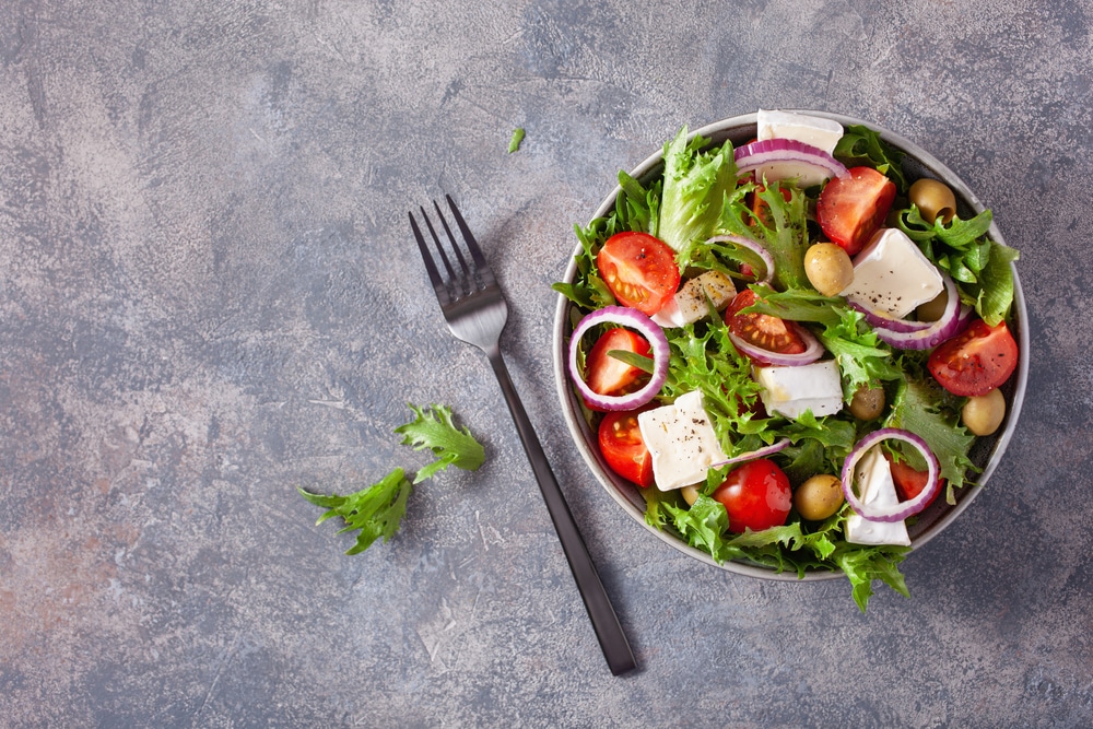 An overhead view of a salad bowl with a fork on side