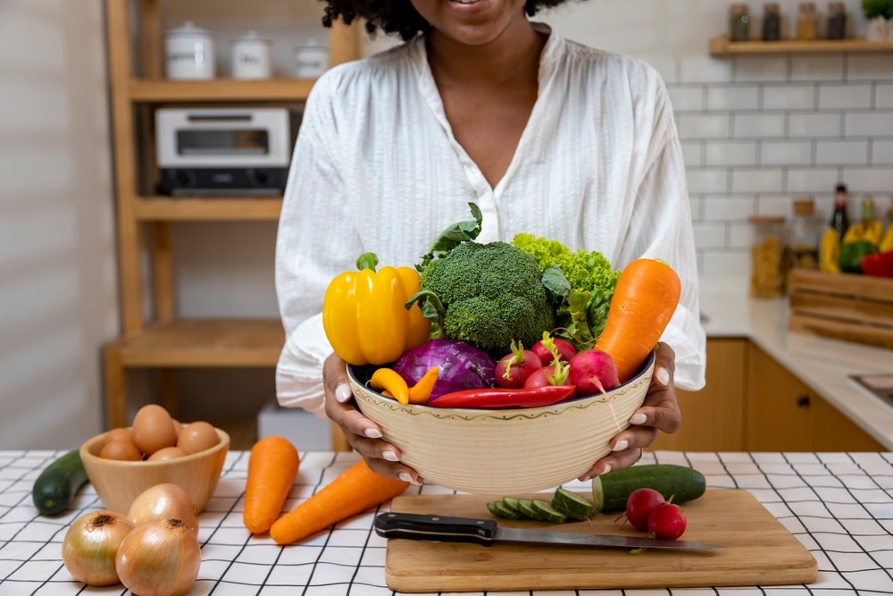 A view of a lady in kitchen with a basket full of veggies