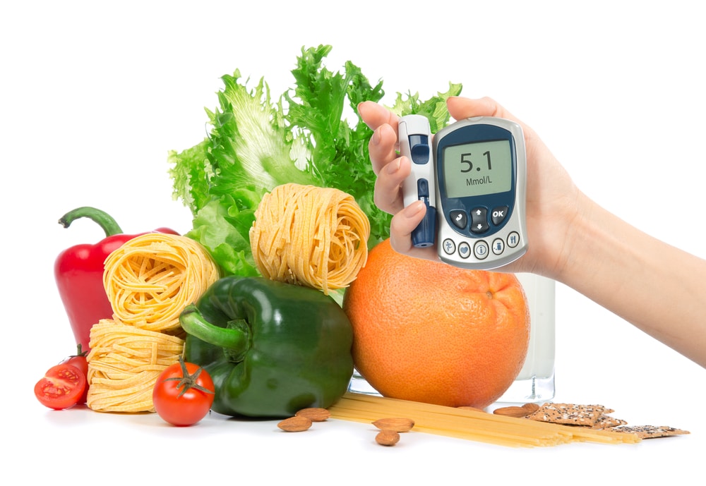 A view of a person holding a glucometer in front of veggies