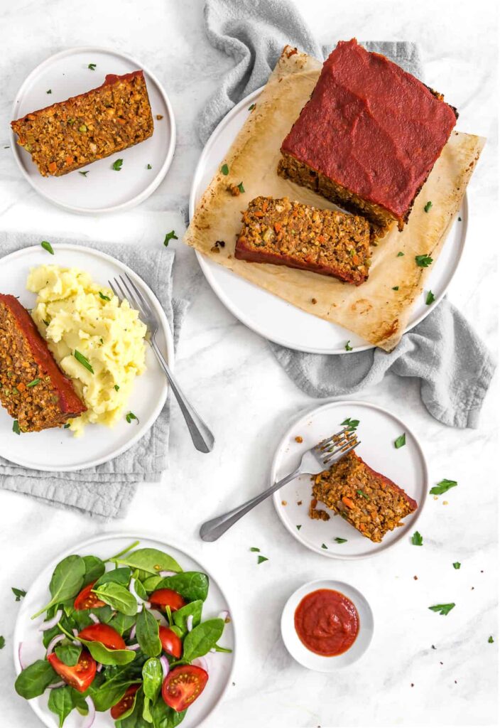 An overhead view of a veggie loaf with mashed potato and some veggie sides plated out