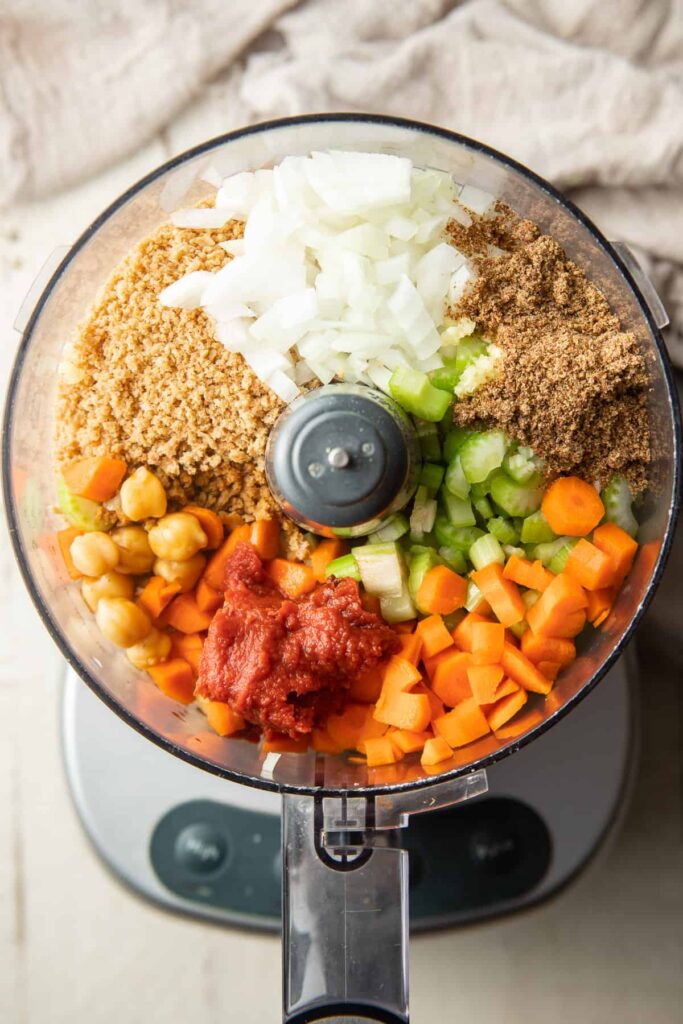 An overhead view of some veggies inside a food processor for a meatloaf recipe