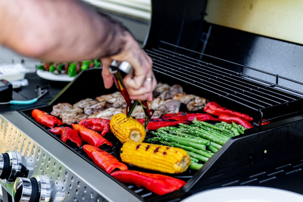 A view of a person flipping a smoked corn with veggies