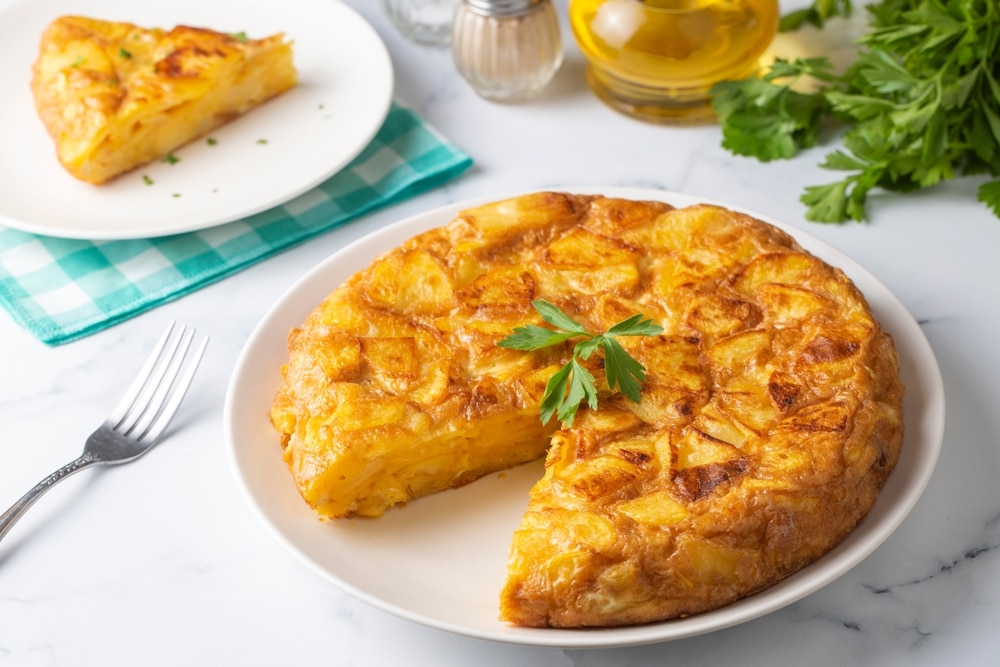 A view of a spanish omelette in a plate with cilantro on top