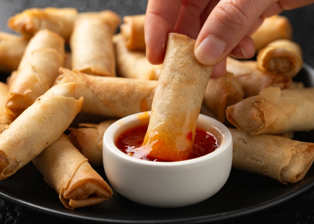 A view of spring rolls dipped in sauce