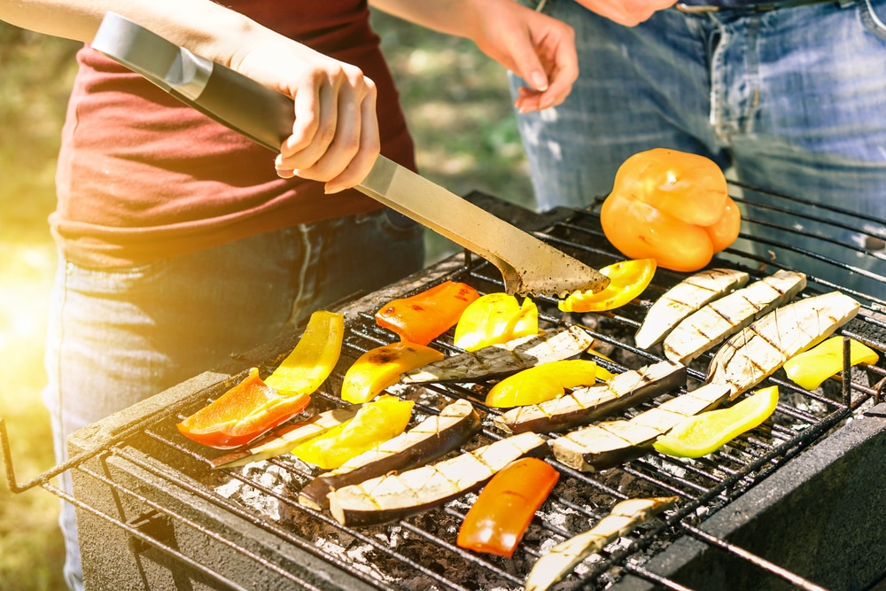 Young Woman Cooking Vegetables For Vegetarian Barbecue Dinner Outdoor