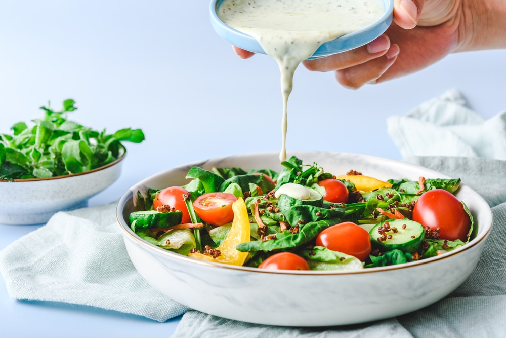 A view of a salad dressing being poured on a salad